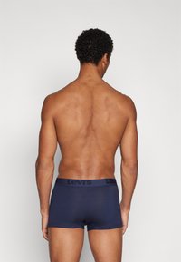 Tengerészkék boxer alsónemű, puha anyagból készült, fekete Levi's logós derékkal. A dizájn testhez simuló, sima textúrával rendelkezik.