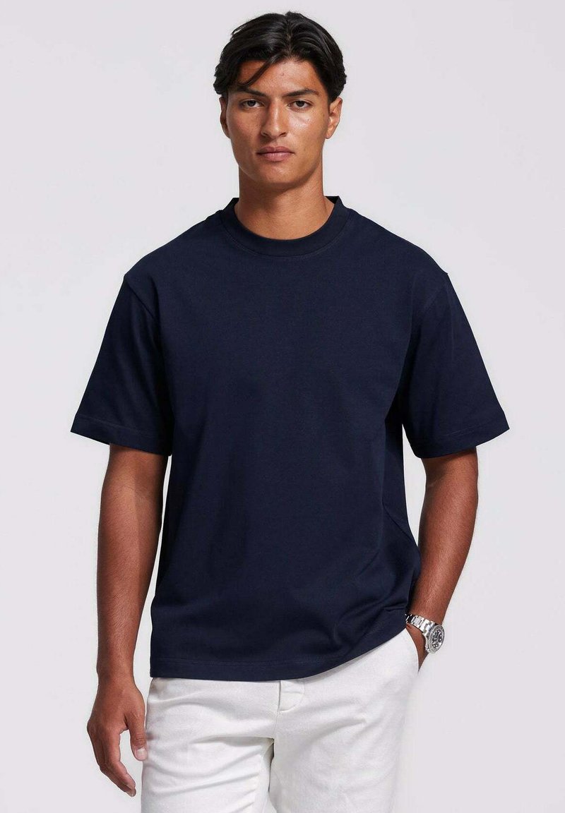 Marineblauwe katoenen t-shirt met een ronde hals en korte mouwen. Eenvoudig ontwerp zonder patronen of accenten, weergegeven op een neutrale achtergrond.