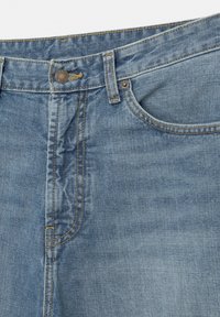Gros plan sur un jean en denim bleu clair montrant le bouton, la braguette à glissière, les passants de ceinture, la poche avant droite et les détails de couture orange.