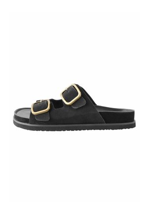 Schwarze offene Sandale mit zwei breiten verstellbaren Riemen mit goldfarbenen quadratischen Schnallen und flacher Sohle.