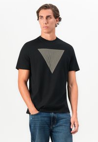 Camiseta negra de manga corta con un gran gráfico de triángulo gris a rayas en la parte delantera. Fabricada con tela suave, diseño ajustado y cuello redondo.