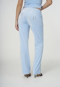 Ljusblå velourbyxor med raka ben. Har "Juicy" i strass på baksidan, mjuk textur och resår i midjan.