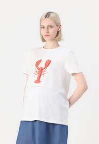 Camiseta de algodón blanca con un gráfico de langosta roja y el texto "SÓLO LLÁMAME EGÓISTA" impreso debajo. Mangas cortas, corte relajado.