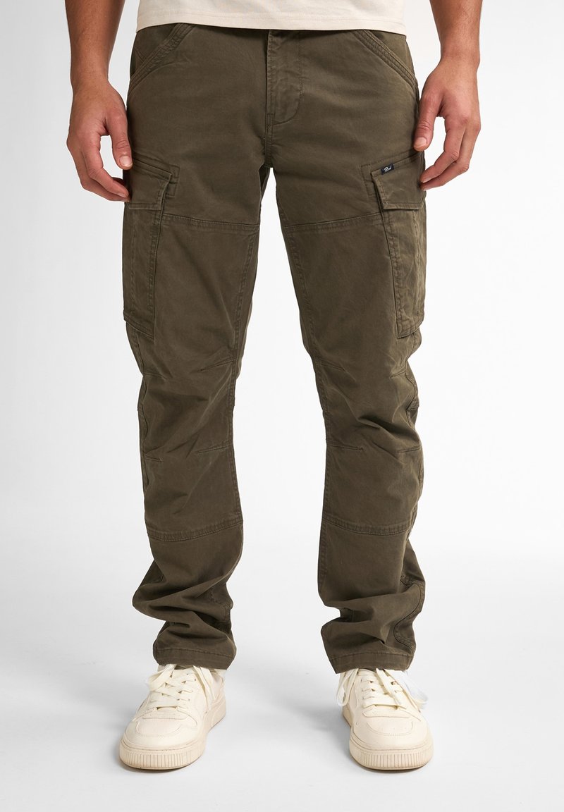 Pantalons cargo vert olive avec plusieurs grandes poches, coupe ajustée et en coton doux. Présente des coutures visibles et une texture usée.