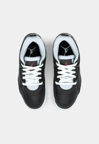 Zapatillas de cuero negro con cordones y entresuela blanca, que presentan un interior azul claro y el logo de Jumpman en la lengüeta y en la plantilla.