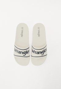Sandale albe cu logo-ul negru "Wrangler" pe curea, realizate dintr-un material de cauciuc neted și având un design plat, cu degetele descoperite.