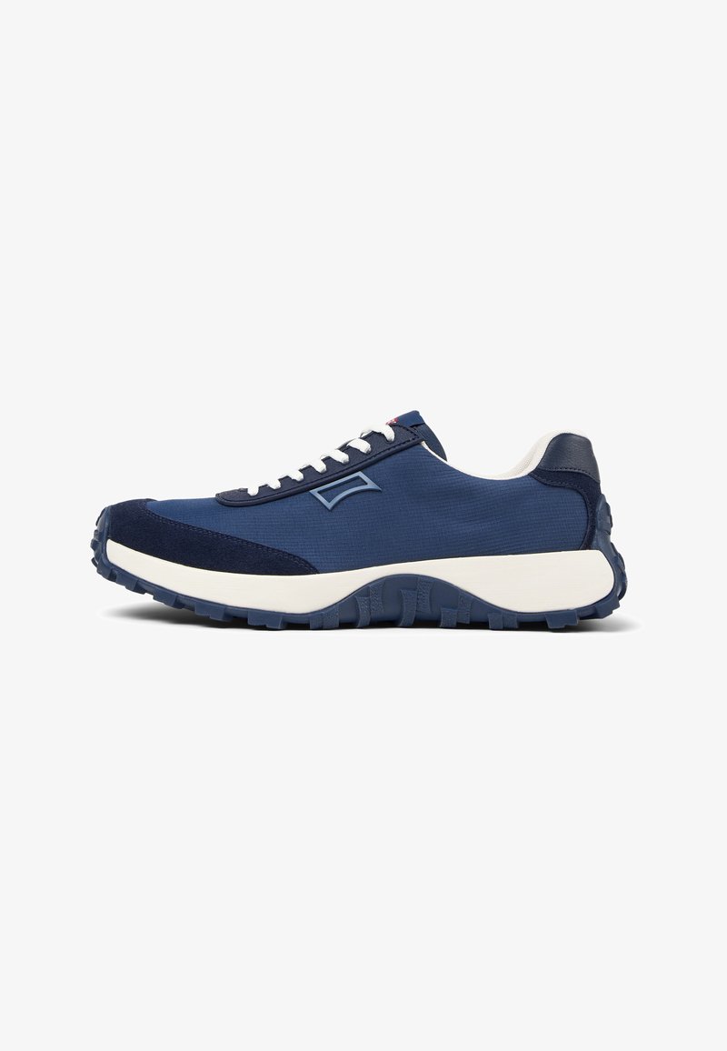 Navy blue athletic shoe with a smooth textile upper, suede accents, and a thick white midsole, featuring a rugged textured rubber outsole.