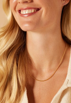 Gouden ketting met een verfijnd ontwerp, met in elkaar grijpende schakels. Draag het om een nek met lichte, losse golven van haar.