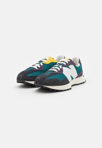 Sneakers med en grön och svart textilöverdel, vit logotyp, lila och gula accenter, vita snören och en strukturerad svart sula.