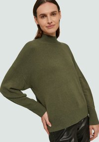 Grüner Strickpullover mit hohem Kragen, lockerer Passform und langen Ärmeln. Rippenbündchen und -saum, aus weichem, strukturiertem Material.