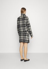 Rutig ullblandad tröja och kjol i svart och krämfärg, med hög halvkrage och avslappnad passform, med mjukt, strukturerat tyg.