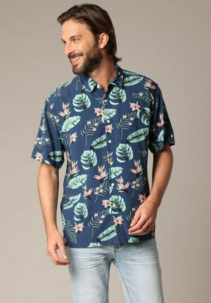 Chemise à manches courtes navy avec de grandes feuilles vertes et des fleurs roses. Tissu léger, design à boutons et coupe ajustée.