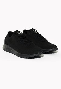 Sneaker nere lavorate a maglia con un design simile a una calza, caratterizzate da una parte superiore texturizzata, chiusura con lacci e suola in gomma per una buona presa.