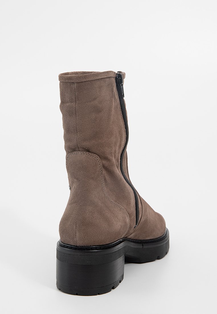 Braune Wildleder-Stiefelette mit einer massiven schwarzen Sohle und einem seitlichen Reißverschluss. Das Design zeichnet sich durch eine glatte Textur und eine runde Zehenform aus.