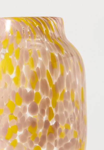 Vase en verre translucide de forme arrondie, décoré de taches jaunes et rose pâle éparpillées sur un fond blanc.