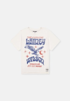 Balta marškinėliai su mėlynu ir raudonu grafikiniu dizainu. Juose pavaizduota erelis, žvaigždės ir tekstas: "AŠ BUVIAU LONESTAR LAINEY WILSON DINAMIKA LINK MĖNULIO."