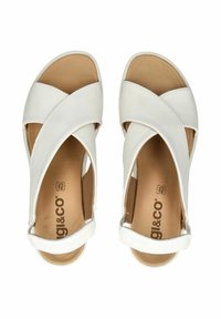 Sandali in pelle bianca con un design incrociato, punta aperta e soletta beige con il nome del marchio stampato all'interno.