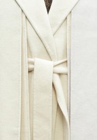 Biely, mäkký župan z látky s klopovým golierom a zodpovedajúcim opaskom, s hladkou textúrou a bezšvovým dizajnom.