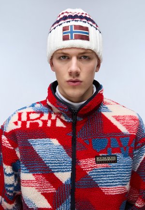 Giacca in pile a motivi rossi e blu con colletto alto e chiusura con zip; cappello lavorato a maglia bianco con patch della bandiera norvegese e accenti blu.