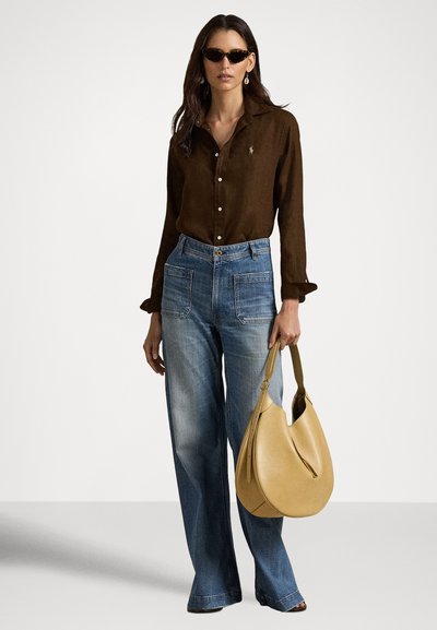 Brūna pogājama krekls, zili plati džinsi, un dzeltens ādas plecu soma. Saulesbrilles un stīpu auskari papildina tēlu.