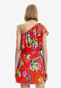 Rød blomsterkjole med én skulderdesign, rynkede detaljer, levende tropiske mønstre og elastisk talje for en tætsiddende silhuet.