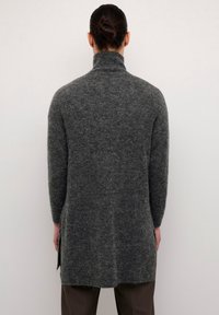 Dunkelgrauer, langärmeliger Rollkragenpullover aus weichem, strukturiertem Material, mit einem seitlichen Schlitz und lockerer Passform, von hinten betrachtet.