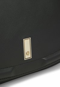 Borsa in pelle nera con superficie testurizzata e un accent in metallo dorato rettangolare con logo inciso.