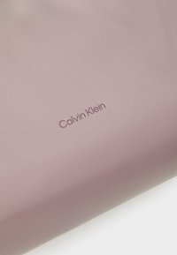 Tessuto in pelle rosa di Calvin Klein con una texture liscia e dettaglio del logo impresso nell'angolo in basso a destra.