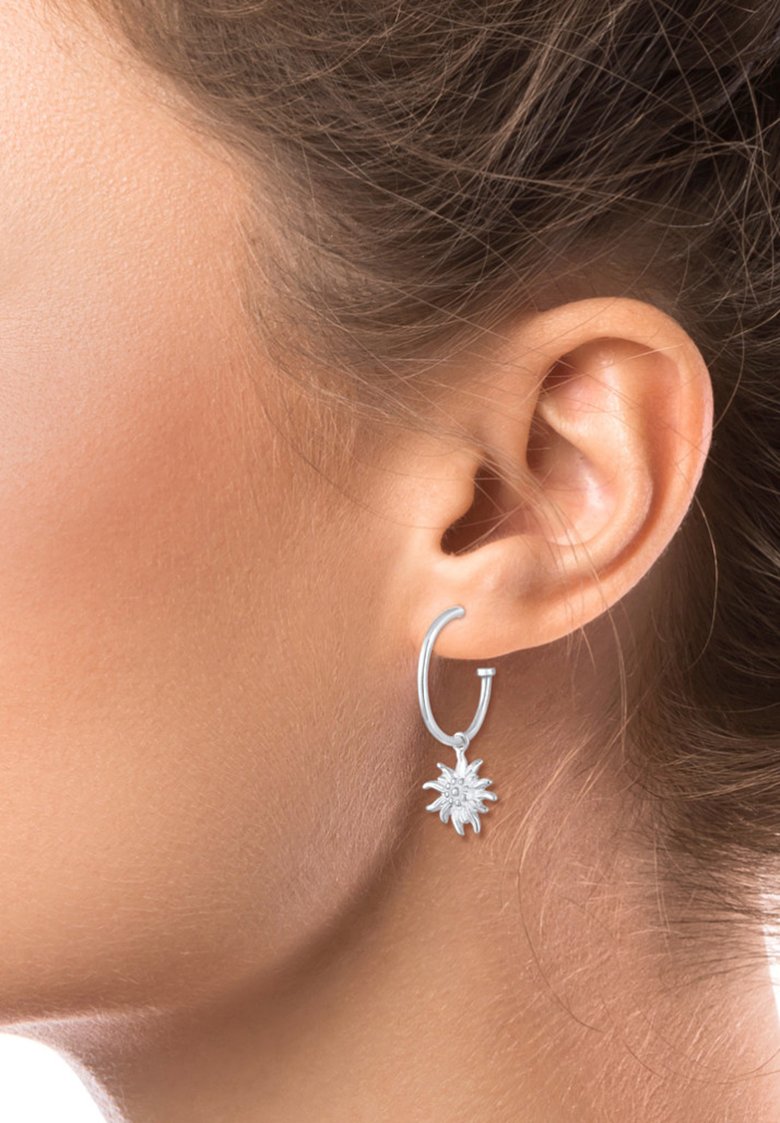 Silberne Creole mit einem Sonnenstrahlen-Anhänger. Der Anhänger verfügt über feine Details und reflektiert das Licht, was visuelles Interesse erzeugt.