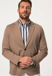 Blazer in tessuto morbido marrone con un bottone singolo e tasca, indossato sopra una camicia a righe. Presenta un design rilassato e informale.