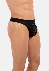 Schwarze Spitzenunterwäsche mit floralem Muster, im niedrigen Schnitt und mit glattem Bund. Der Stoff hat eine transparente, zarte Textur.