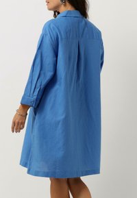 Blå langermet skjortedress i lett stoff, med krage som kan åpnes, avslappet passform og sidel pleats.