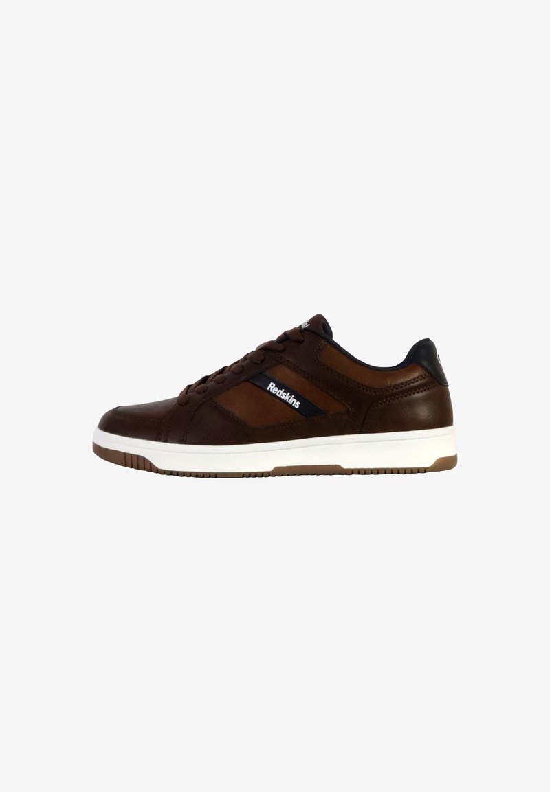 Baskets en cuir marron avec semelle en caoutchouc blanche, présentant des accents noirs et le logo "Redskins", caractérisées par un design épuré et sportif.