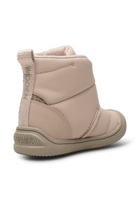 Botte d'hiver rose blush pour tout-petit avec côtés rembourrés, semelle beige texturée et languette de tirage marquée à l'arrière.