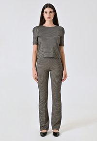 Set coordinato a quadri in bianco e nero, composto da un top a maniche corte e pantaloni aderenti, realizzati in tessuto texturizzato, con orlo cropped e gambe a zampa.