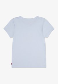 Φωτεινό μπλε μπλουζάκι, κοντά μανίκια, στρογγυλή λαιμόκοψη, λείο βαμβακερό ύφασμα, απλό σχέδιο, με μικρή ετικέτα μάρκας στο κάτω αριστερό μέρος.