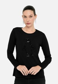 T-shirt nero a maniche lunghe con un design di pinguino impreziosito da paillettes al centro. Il tessuto sembra liscio con un colletto rotondo.