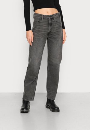Jeans pretos de cintura alta com um corte largo, apresentando bolsos frontais, fecho com zíper e detalhes de desbotamento subtil. Textura de denim suave.