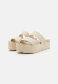 Sandali platform beige con doppie cinghie in tessuto, una base spessa, suola esterna testurizzata e dettaglio di branding minimal sulla cinghia superiore.