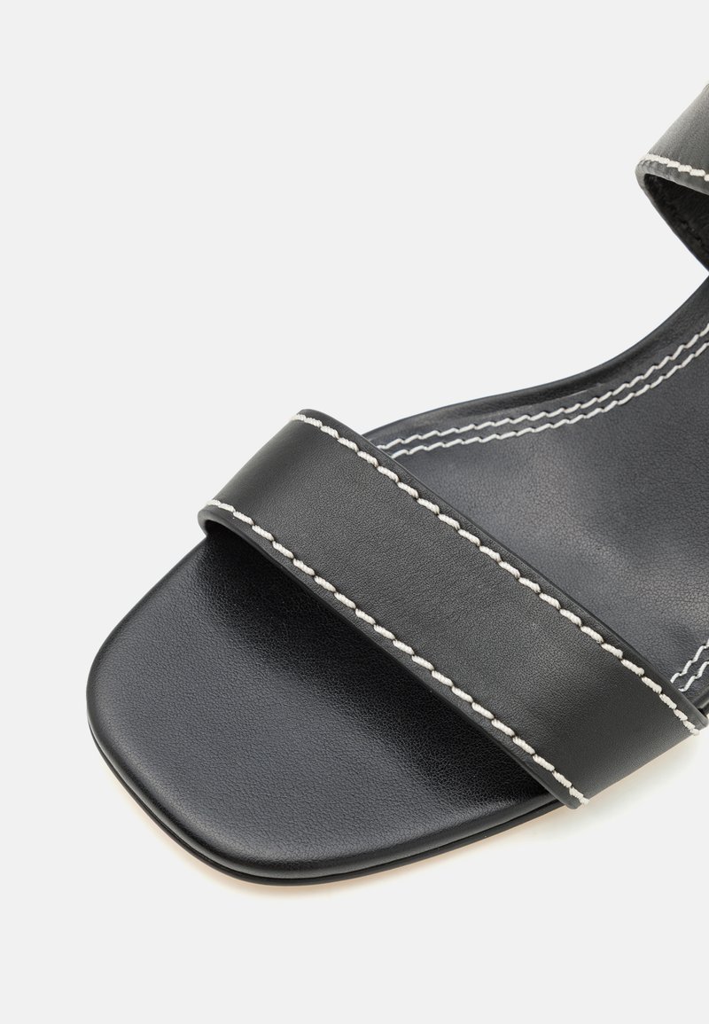 Czarne skórzane sandały z dwiema szerokimi paskami, białymi przeszyciami, kwadratowym noskiem oraz gładką, teksturowaną cholewką o minimalistycznym designie.