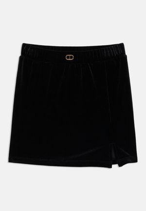 Saia de veludo preto com cintura elástica, apresentando um detalhe de metal dourado e uma fenda do lado direito. Textura suave.