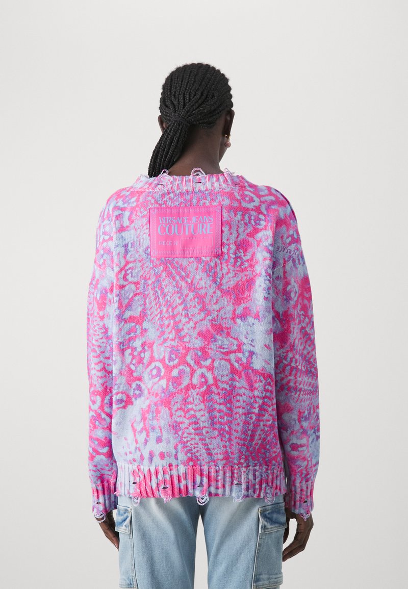 Roze en blauwe gebreide trui met een geribbelde zoom, versleten randen en een opvallend logo-opdracht op de achterkant. Casual brei-design.