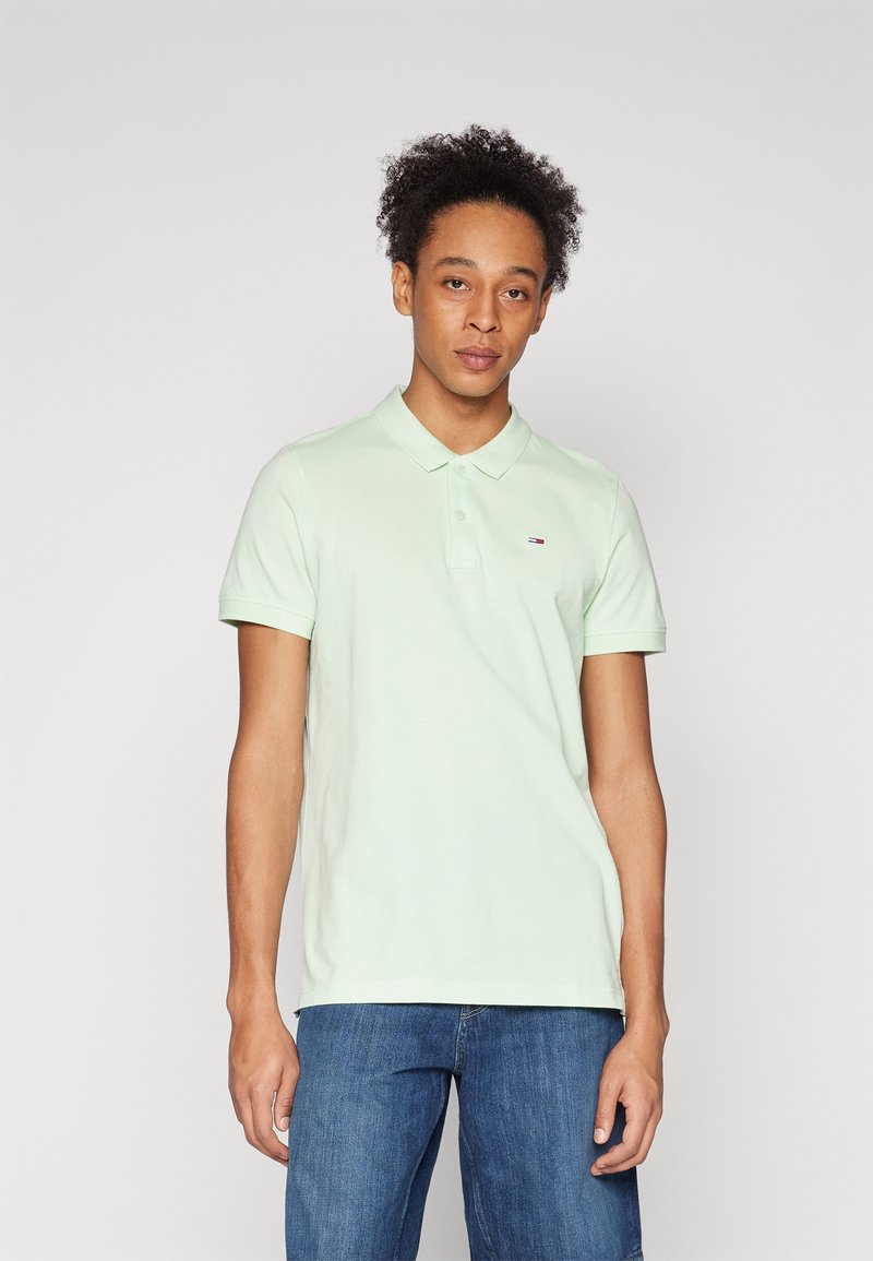 Lys grønn polo skjorte med krage, kort ermer og en liten logodetalj. Brukt sammen med blå jeans, minimalistisk design.