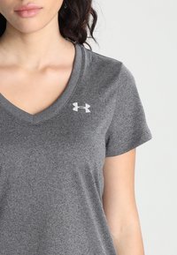Graues V-Ausschnitt-T-Shirt aus weichem, strukturiertem Stoff. Kurze Ärmel und ein kleines weißes Under Armour-Logo auf der oberen linken Seite.