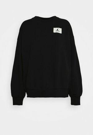 Felpa nera a maniche lunghe con scollo a girocollo, polsini a costine e una piccola toppa bianca sul petto con il logo Jumpman nero.