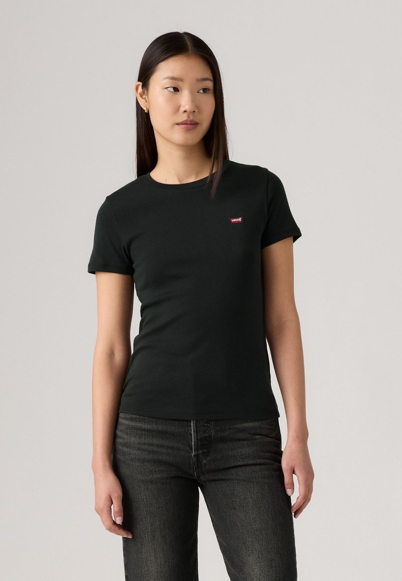 T-shirt noir à col rond en coton, avec des manches courtes et un petit logo rouge Levi's sur la poitrine gauche. Tissu texturé.