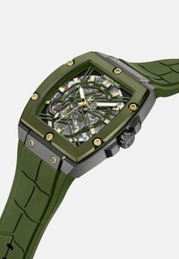 Quadratische Automatikuhr mit grünem Silikonarmband und -gehäuse, ausgestattet mit einem transparenten Skelettzifferblatt, goldenen Akzenten und silbernen Beschlägen.