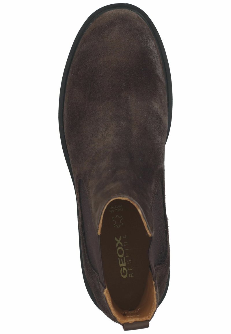 Brązowy zamszowy boot z elastycznymi bocznymi panelami, okrągłym noskiem i gumową podeszwą. Wewnątrz znajduje się wkładka z logo na ciemnym tle.