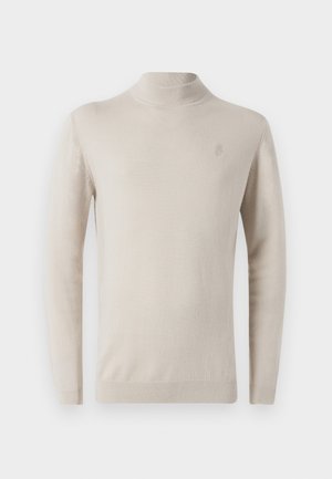 Pull à col roulé beige en tissu doux, ajusté, avec des manches longues et un logo brodé subtil sur la poitrine.