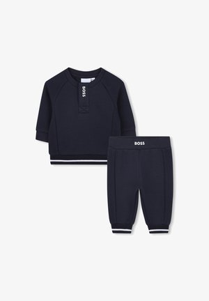 Granatowy zestaw dresowy dla dzieci składający się z krótkiego rękawka z teksturą ściśniętą oraz spodni z elastycznymi mankietami i białymi akcentami.